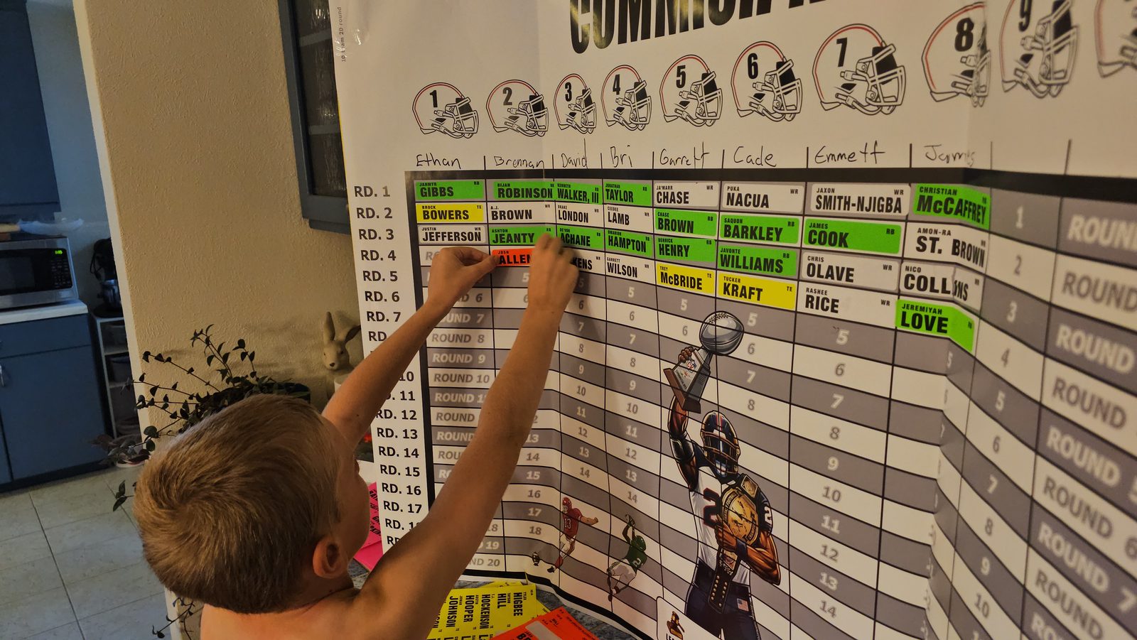 A young kid reaching up to place a player sticker onto the draft board