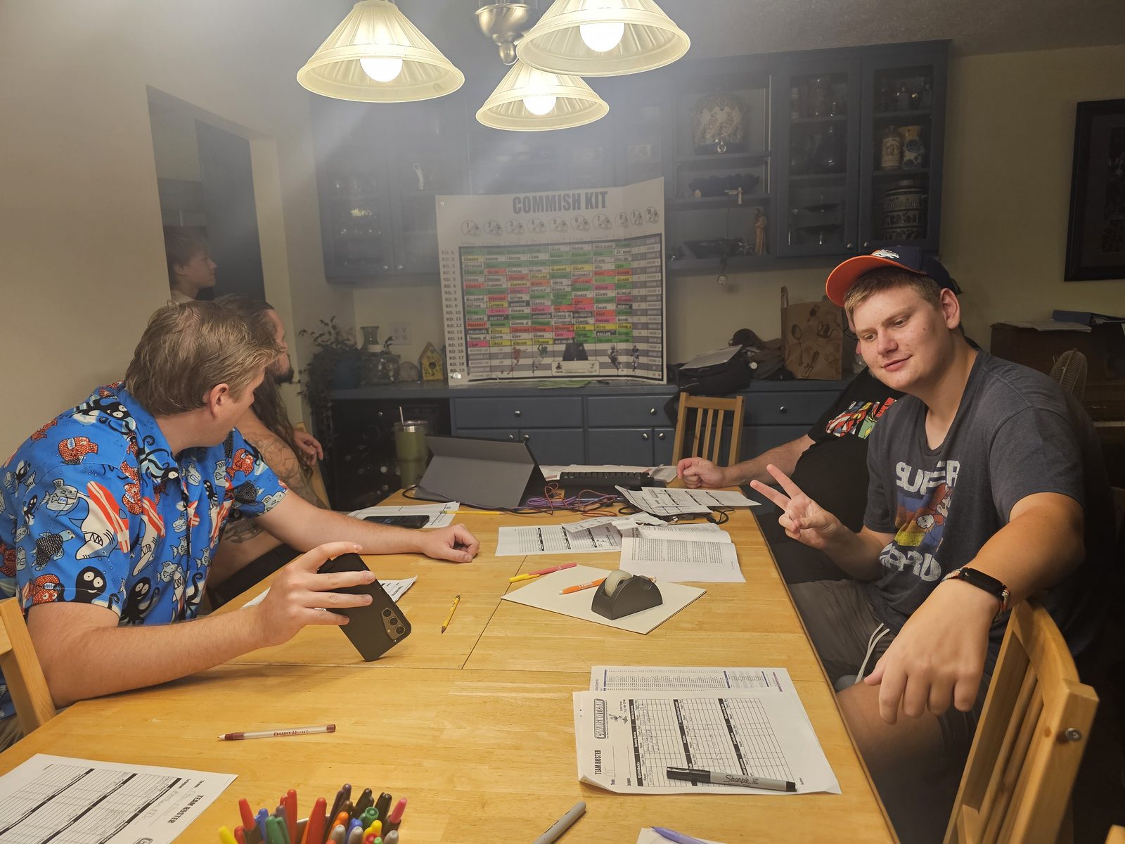 Two managers at the table mid-conversation, one holding a phone, the other making a peace sign